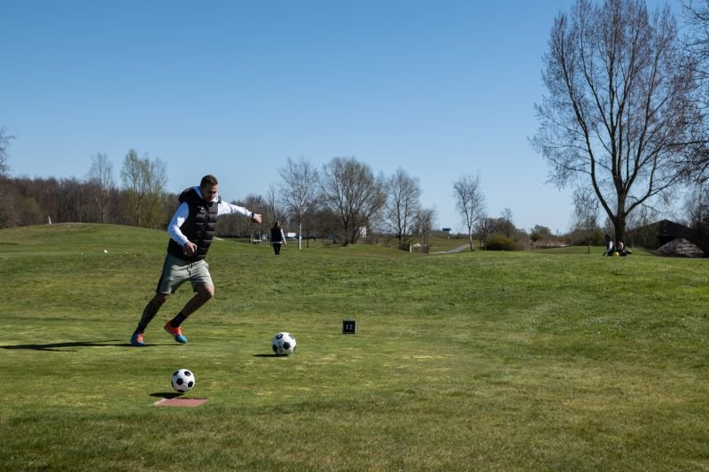 Speler trapt een voetbal op de baan