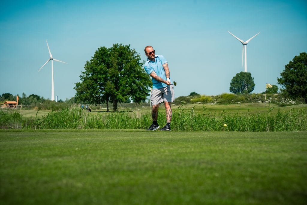 Golfer slaat af met windmolens op de achtergrond