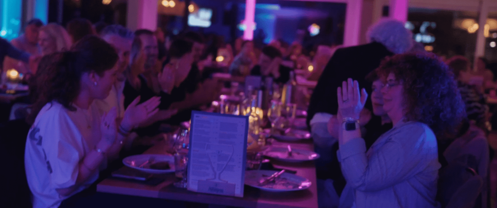 Gedekte tafels in een zaal met paarse verlichting