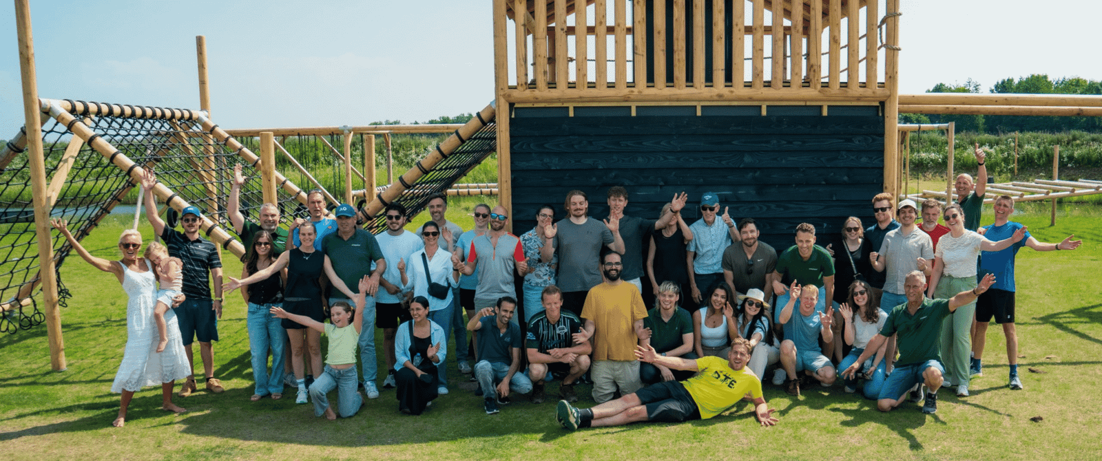 Grote groep poseert bij een houten klimtoestel