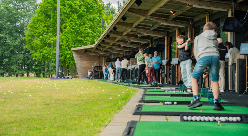 Overdekte afslagplaatsen met bezoekers bij de driving range